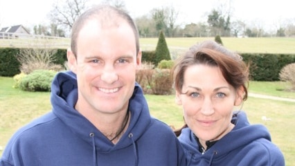 Andrew Strauss and wife Ruth stand arm in arm on a green lawn.