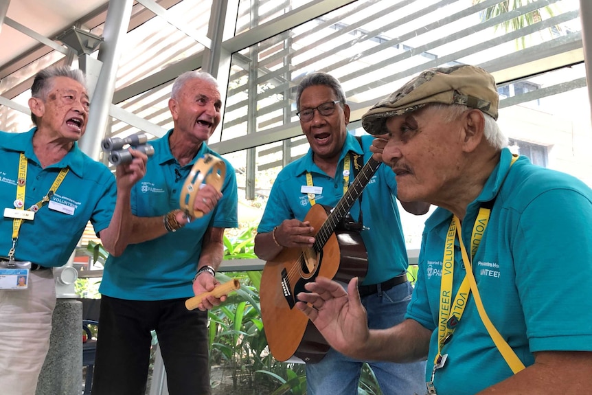 Four older gentlemen play their instruments in the foyer of the PA hospital.