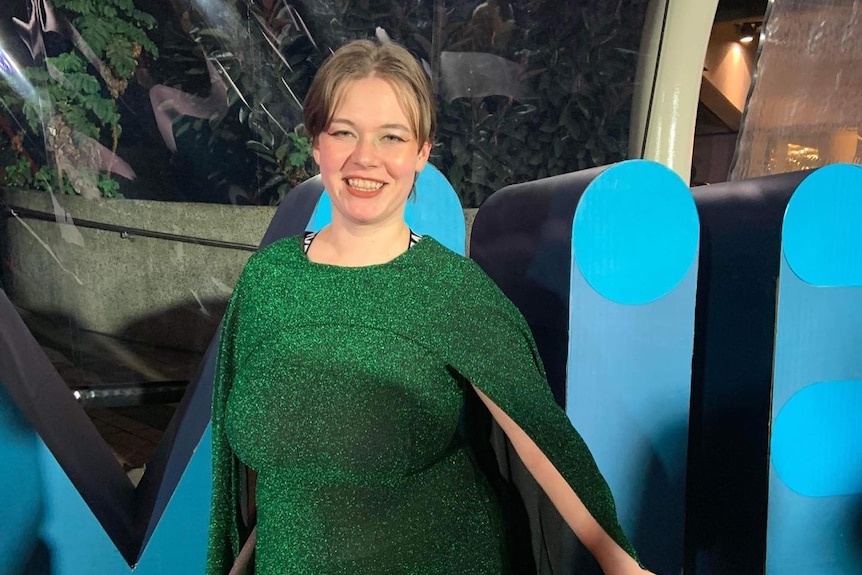 Silvi Vann-Wall dressed-up at an event in a shimmering green pantsuit with a built-in cape