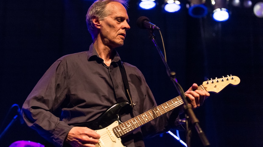 Tom Verlaine playing the guitar on stage in 2019
