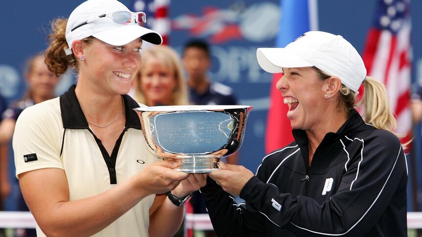 Samantha Stosur and Lisa Raymond laugh while holding US Open doubles trophy