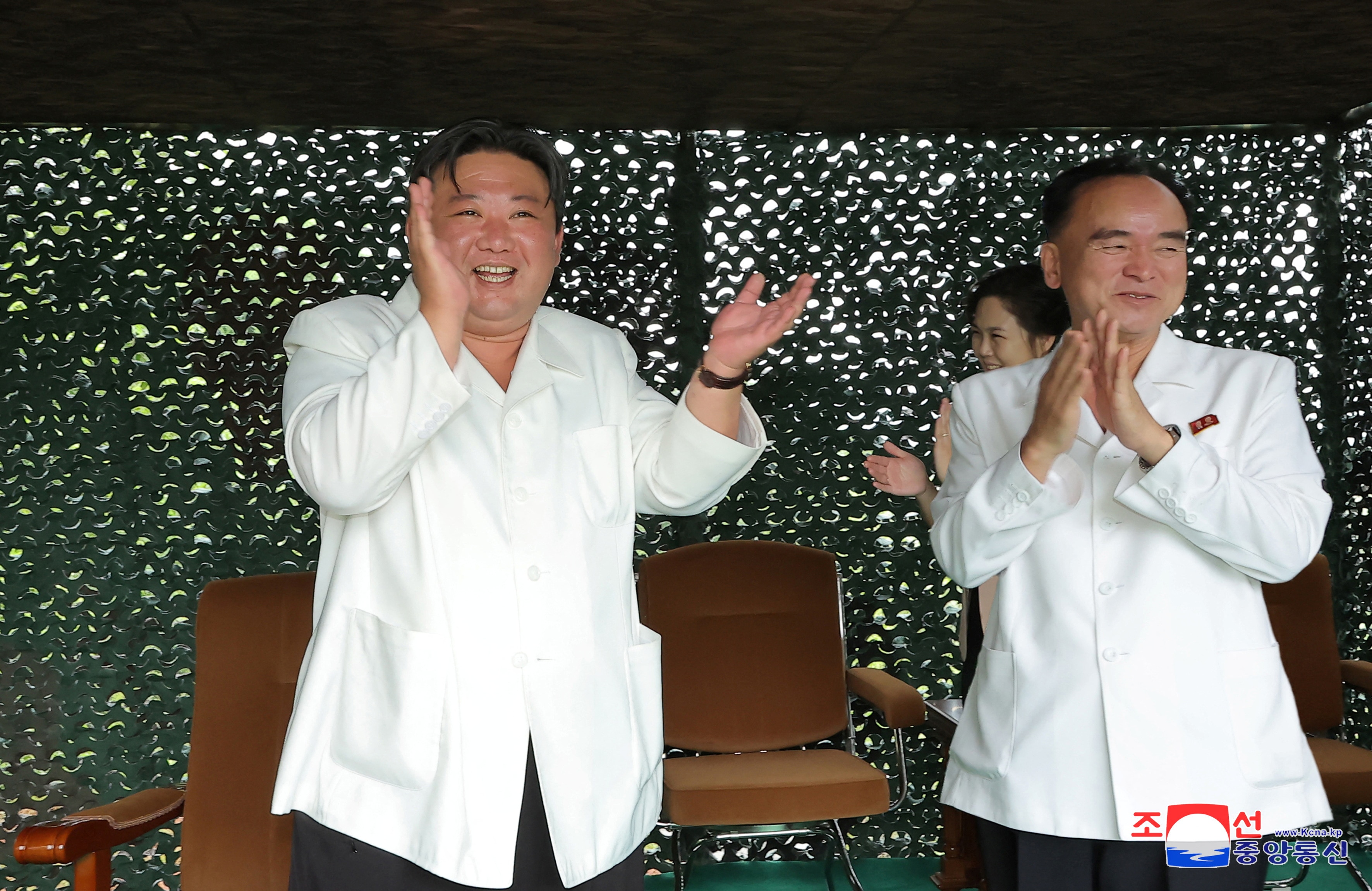 Kim Jong Un and another man both applaud 