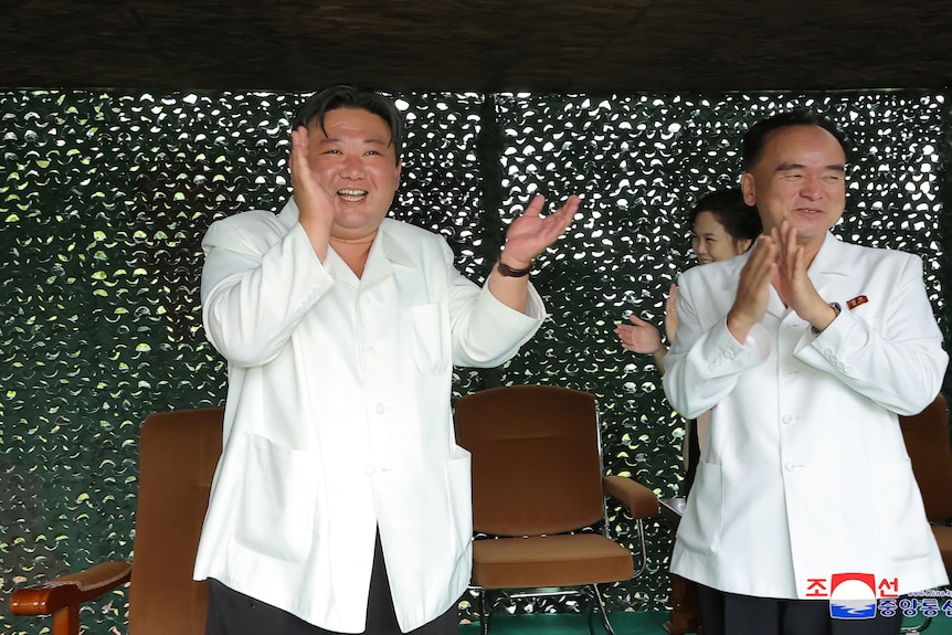 Kim Jong Un and another man both applaud 