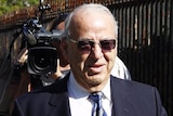 Upper body photo of Eddie Obeid arriving at the Supreme Court, followed by a TV camerman.