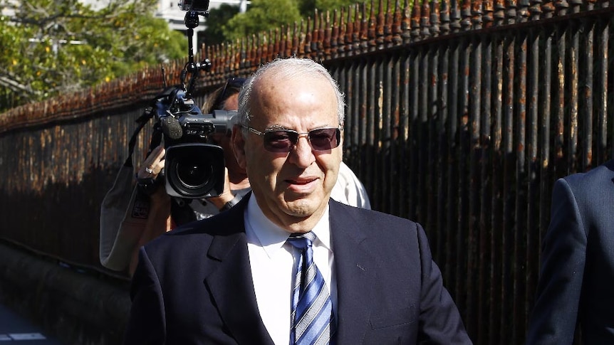 Upper body photo of Eddie Obeid arriving at the Supreme Court, followed by a TV camerman.