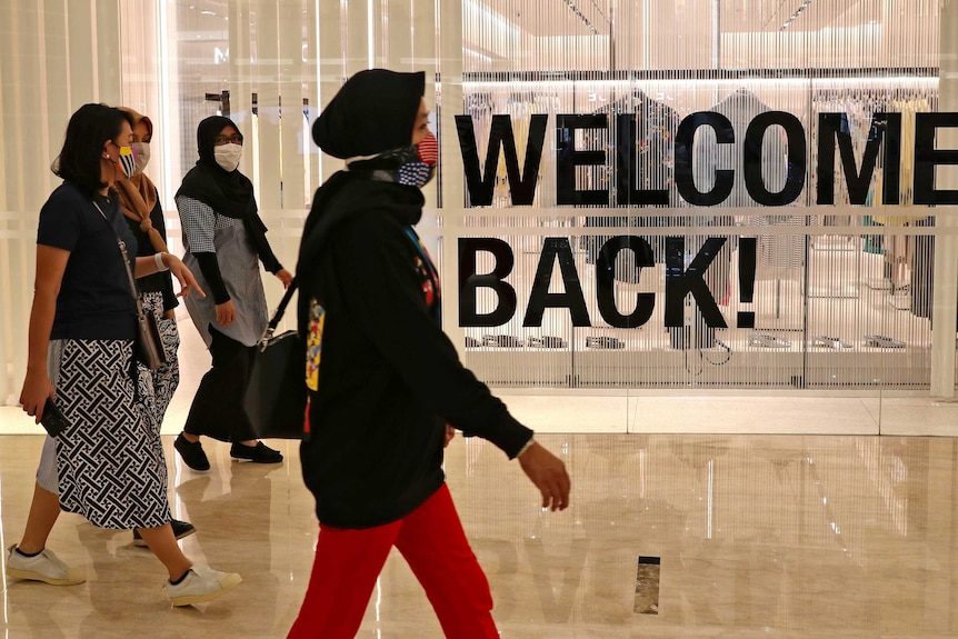 Visitors wearing protective masks walk through a shopping mall in Jakarta after its reopening.