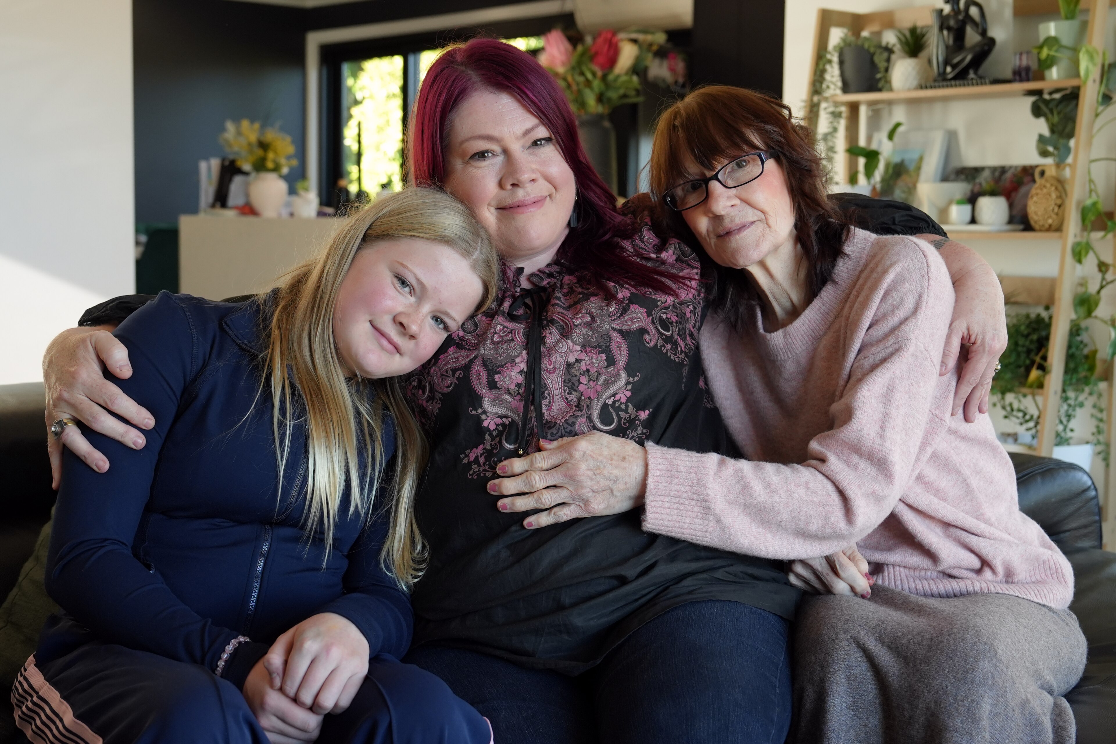 Three generations of women sitting on a couch.