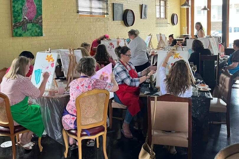 A room full of women paint on canvasses in Ms Jenning's tea room and wine bar.