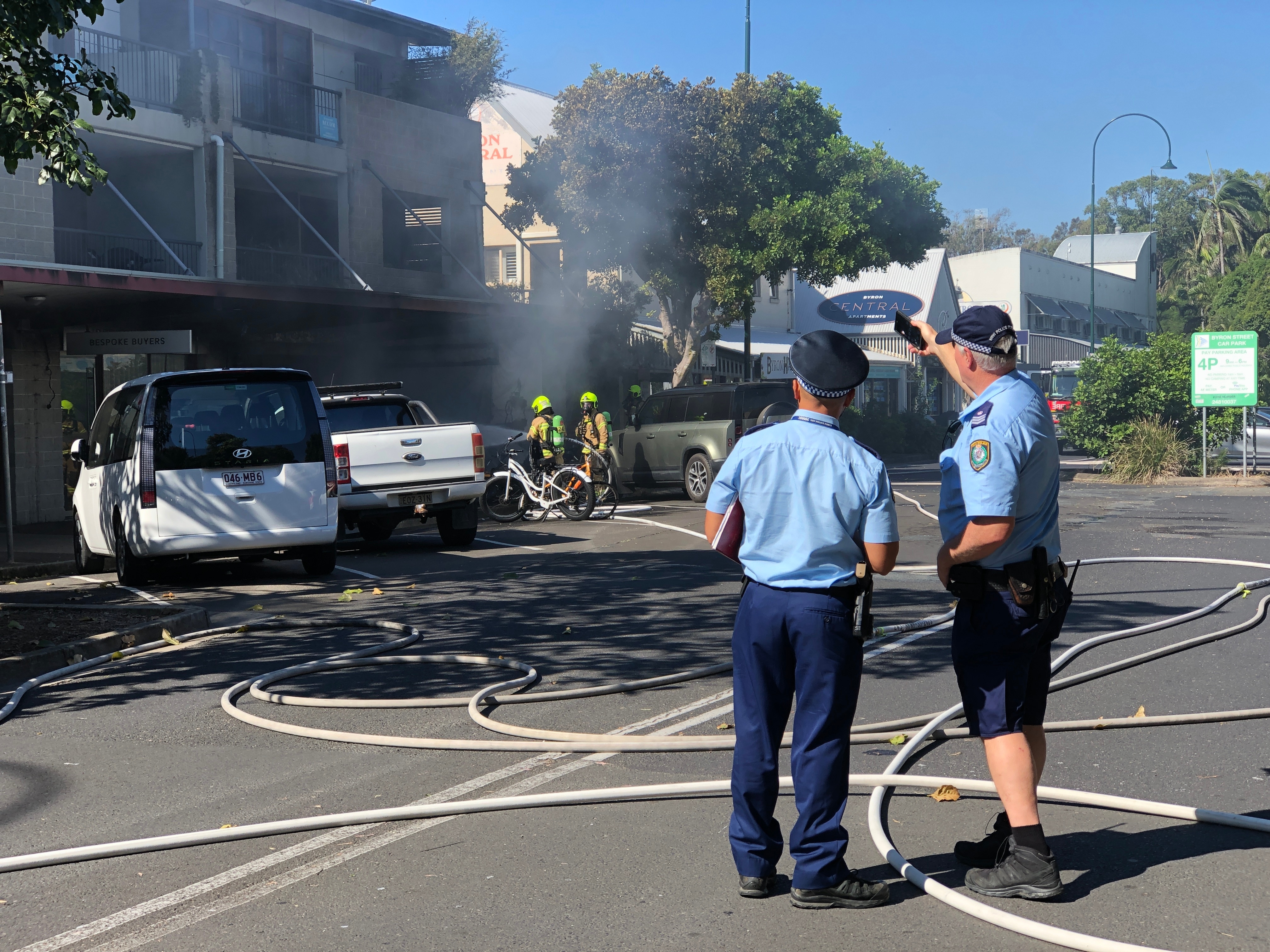 Dos agentes de policía se encuentran frente a un edificio incendiado.