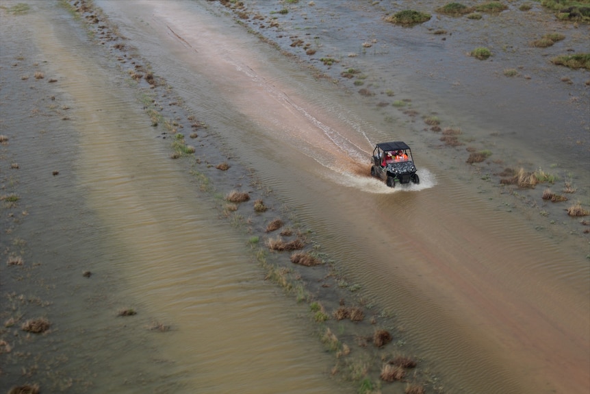 A buggy drives through shallow floodwater.