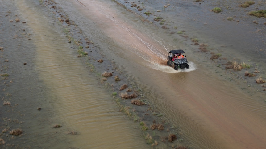 A buggy drives through shallow floodwater.