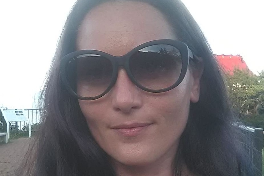 A woman in sunglasses smiling at the camera.