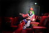 Brightly dressed clown sitting in cinema seats