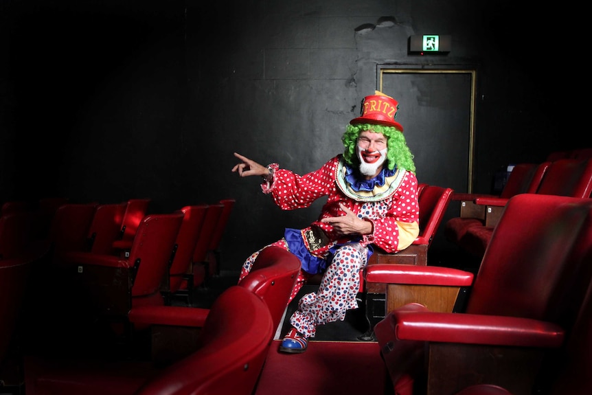 Brightly dressed clown sitting in cinema seats