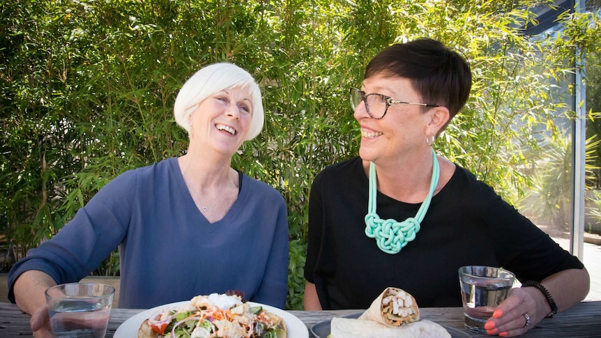 Two women laugh while sharing a meal at an outdoor table at a Warracknabeal pub.