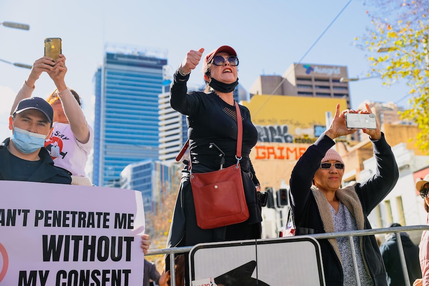 A woman carrying a red bag at protest raising her fist