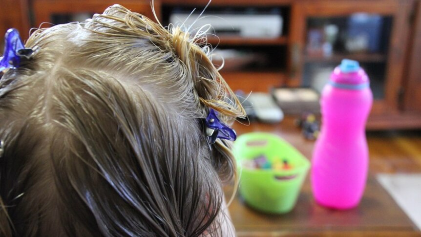 A young girl is treated for headlice.