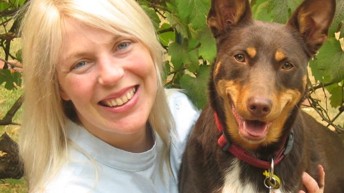 A woman with blonde hair next to a brown kelpie