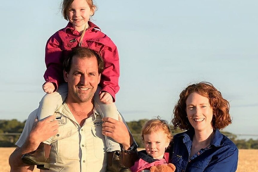 Family of four, husband, wife and two daughters on a farm.  
