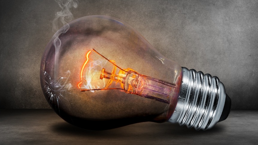 A lightbulb sits on a fat surface, glowing orange and emitting smoke.