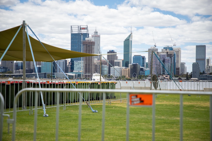 Marquees set up along a river foreshore with the city skyline in the background