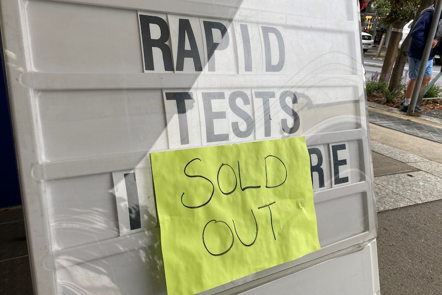 A handwritten "sold out" note taped to a rapid antigen test sign.