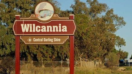 A sign on the side of a country road that reads "Wilcannia".