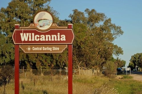 A sign on the side of a country road that reads "Wilcannia".