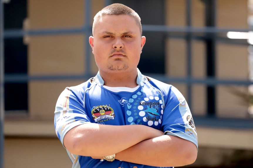 A portrait of a young man with short hair and arms crossed