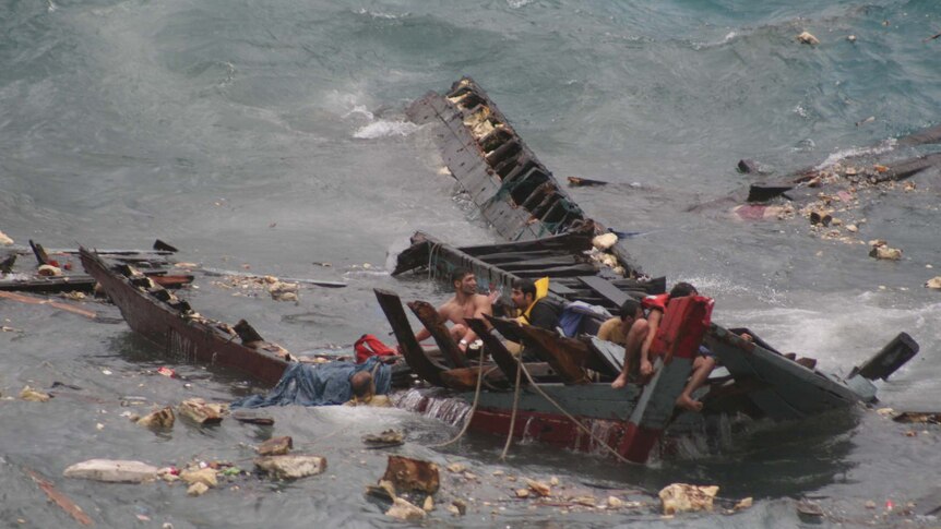 People cling to the remains of a boat that was smashed in a shipwreck on Christmas Island