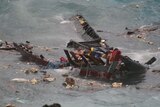 People cling to the remains of a boat that was smashed in a shipwreck on Christmas Island