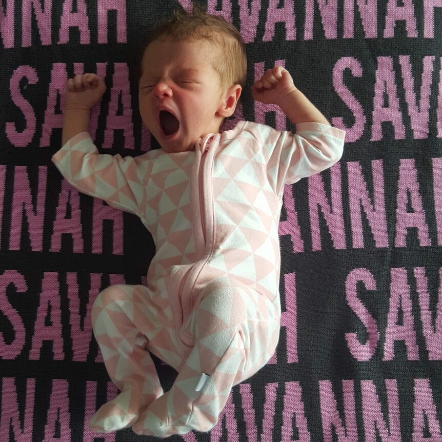 a baby girl lies on a blanket emblazoned with her name "Savannah"