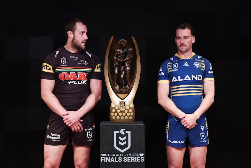 Isaah Yeo and Clint Gutherson stand next to the NRL trophy