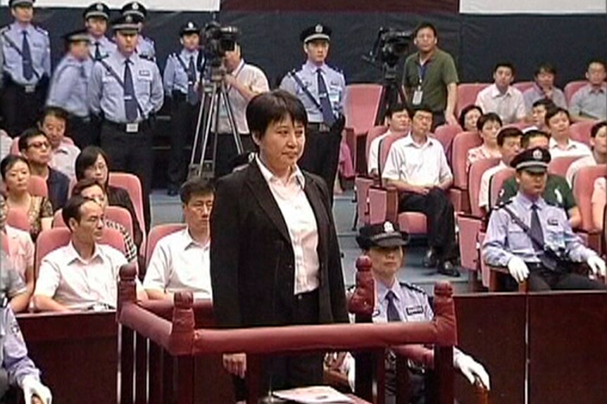 A woman stands up in a crowded court room 