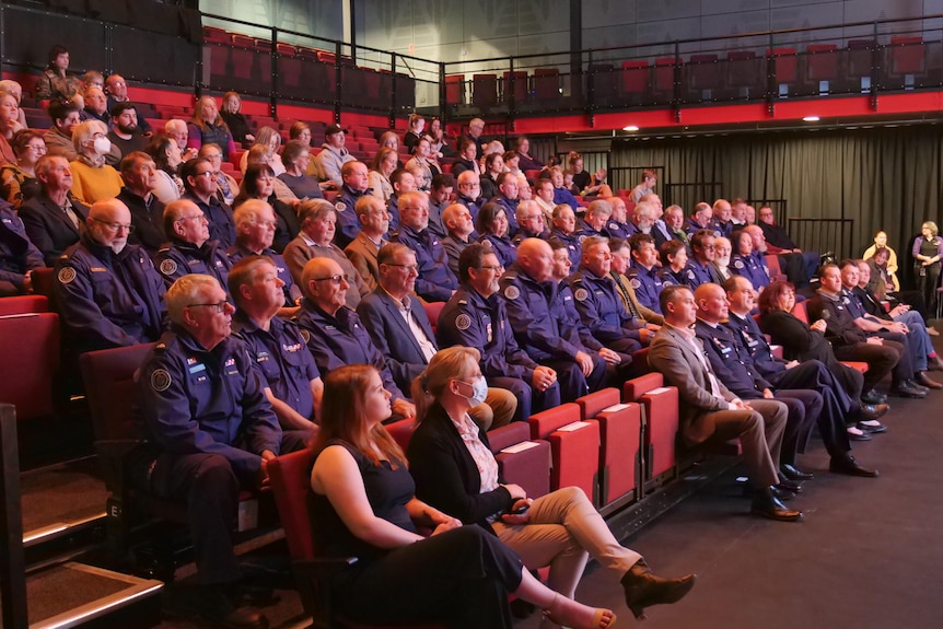 A large group of people in sit in tiered seating at an awards ceremony.