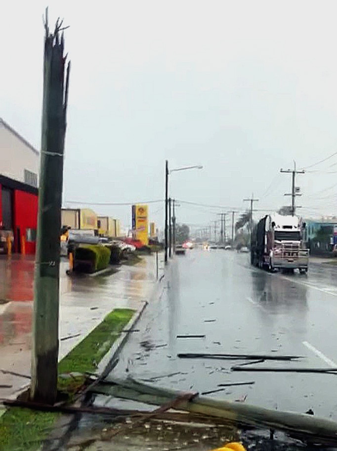 A power pole split in half, the broken section lying on a road