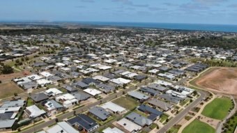 A drone photo of a new housing estate with the ocean in the distance.