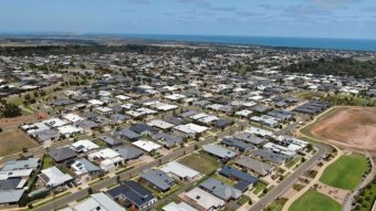 A drone photo of a new housing estate with the ocean in the distance.