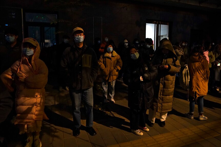 Supporters of Zhou Xiaoxuan wearing face masks wait outside a courthouse in a cold night in Beijing