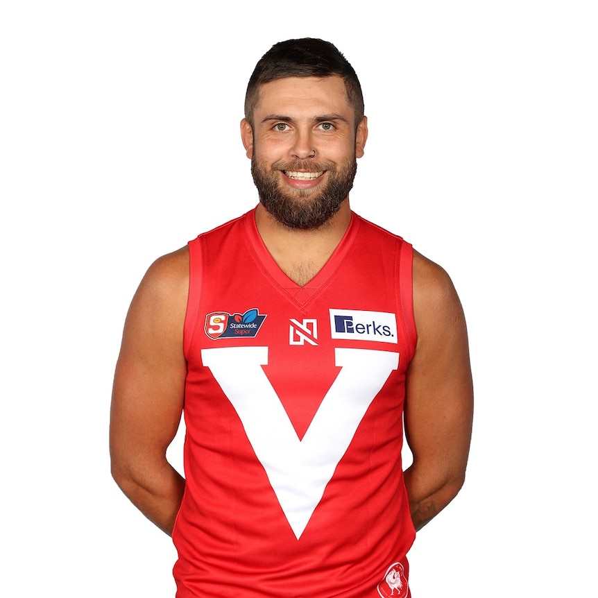 A man wearing a red Australian rules guernsey with a white V on it