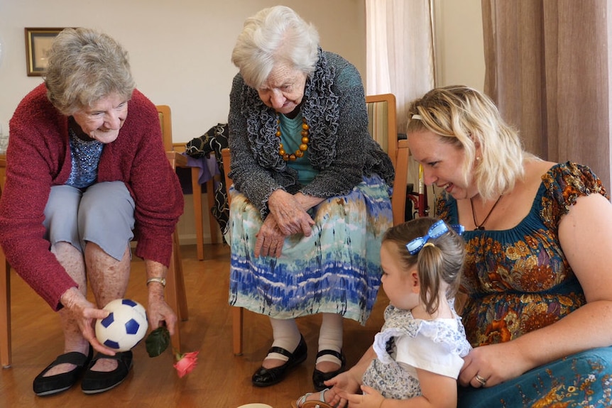Pamela McLean and another aged care resident play with 19-month-old Aliyah and her mum Samantha.