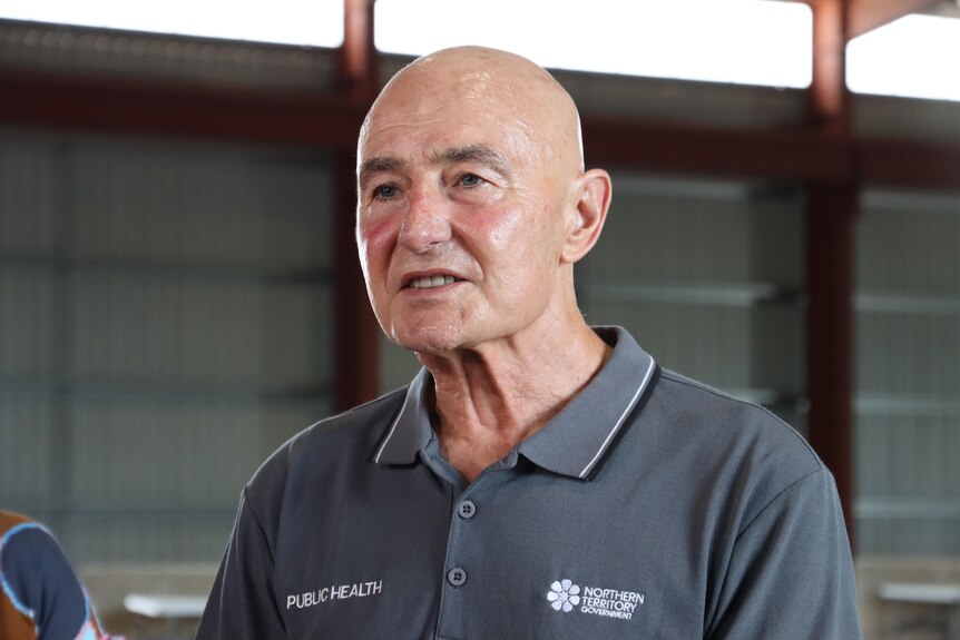 a bald man wearing a collared shirt speaks in a shed