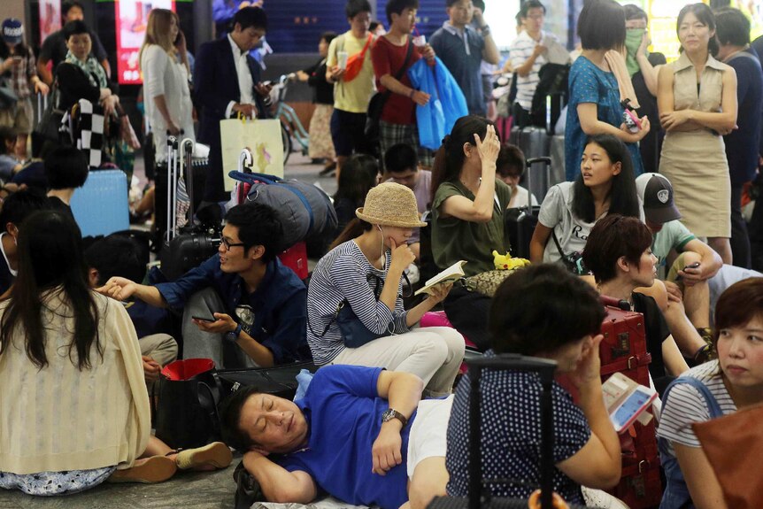 Japanese passengers wait for train service to resume as typhoon passes