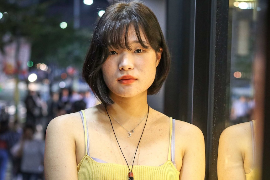 A woman poses straight-on to the camera at night time