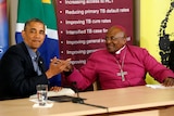 Barack Obama in a dark suit shakes hands wiht Demond Tutu in his pink archbishop robes.