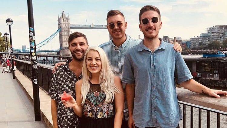 A group of friends pose in front of a bridge on London's River Thames