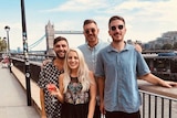 A group of friends pose in front of a bridge on London's River Thames