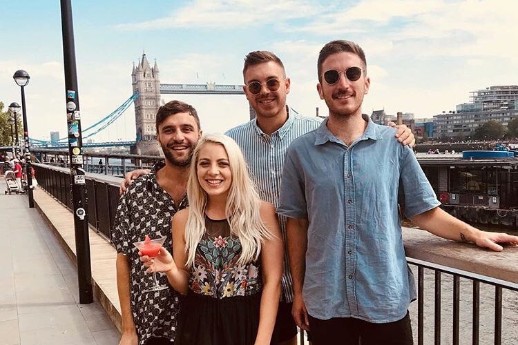 A group of friends pose in front of a bridge on London's River Thames