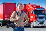 A woman, with a camera over her shoulder, stands in front of a big red truck