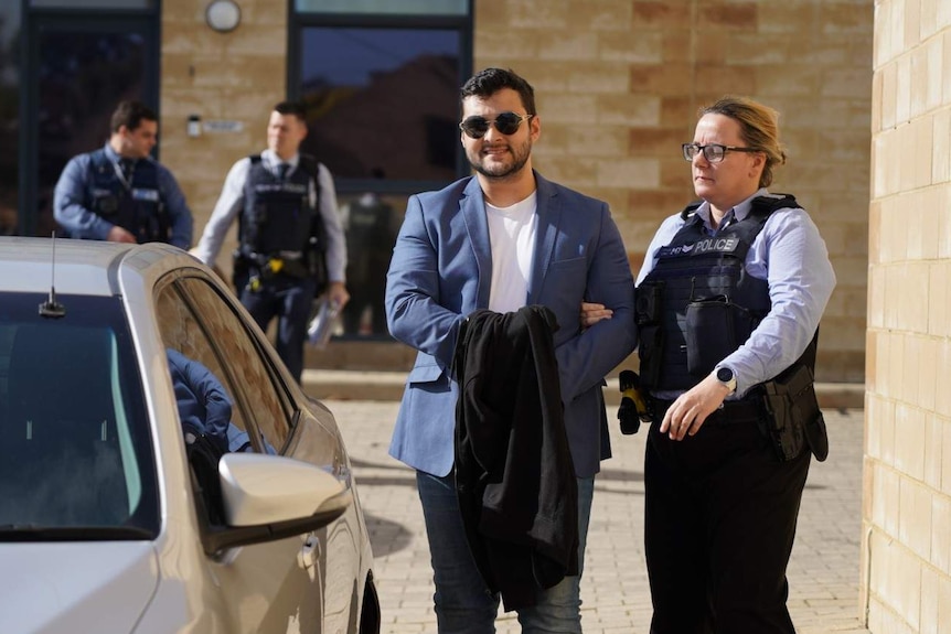 Tyson Vacher being escorted by a police woman into an unmarked car.